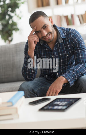 Hispanic Mann mit Handy und digital-Tablette im Wohnzimmer Stockfoto