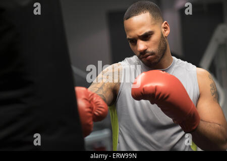 Close up Portrait of Hispanic Mann Boxsack im Fitness-Studio Stockfoto