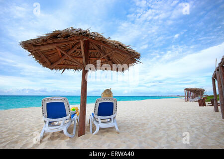 Famale Tourist mit Hut sitzt unter Sonnenschirm Karibik Meer am weißen Sandstrand in Cayo Santa Maria, Kuba Stockfoto