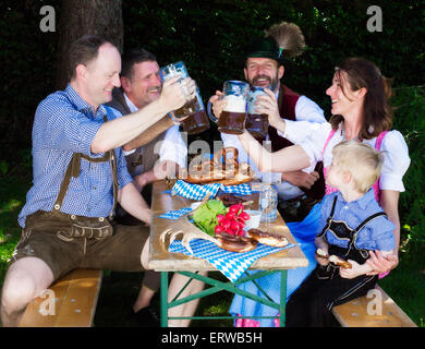 bayerischen Familie draußen auf einer Bank und trinken Bier Stockfoto