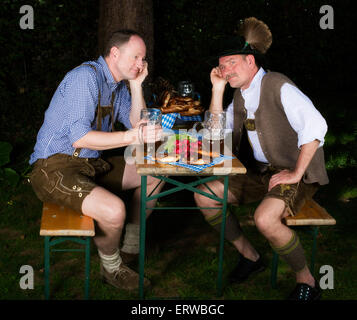 zwei bayerische Männer sitzen in einem Park, gelangweilt, Bier trinken und auf der Suche Stockfoto