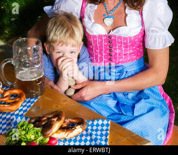 kleinen bayerischen blonde Junge sitzt neben seiner Mutter Stockfoto