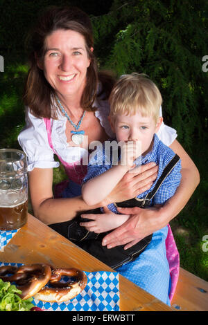 kleinen bayerischen blonde Junge sitzt neben seiner Mutter in einem Biergarten Stockfoto