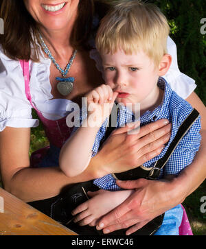 kleinen bayerischen blonde Junge sitzt neben seiner Mutter Stockfoto