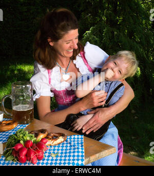 kleinen bayerischen blonde Junge sitzt neben seiner Mutter in einem Biergarten Stockfoto