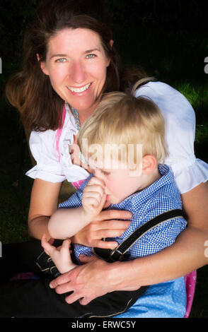 kleinen bayerischen blonde Junge sitzt neben seiner Mutter Stockfoto