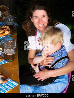 kleinen bayerischen blonde Junge sitzt neben seiner Mutter in einem Biergarten Stockfoto