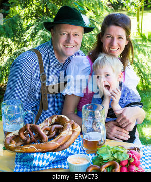 bayerischen Familie draußen auf einer Bank und lächelnd Stockfoto