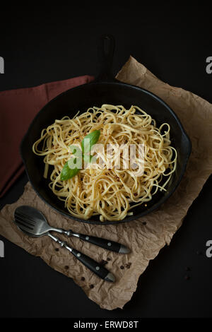 Linguine sitzt in einer schwarzen gusseisernen Pfanne auf eine schwarze Fläche mit einer zerknitterten braune Papiertüte unter. Stockfoto