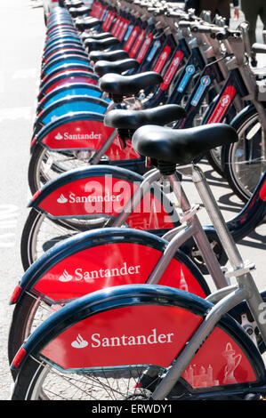 Santander-Sponsoring auf eine Reihe von Boris-Bikes zu mieten in London, mit einigen älteren Barclays gesponsert Fahrräder im Hintergrund. Stockfoto