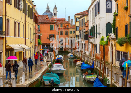 Touristen unter Sonnenschirmen an einem regnerischen Tag in Venedig Stockfoto