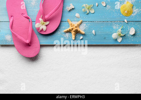 Flip-Flops mit Muscheln am Strand Stockfoto