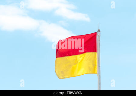 Rote und gelbe Sicherheitsflagge einen Strand, der Bademeister hat Stockfoto