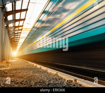 High-Speed-Personenzug auf Strecken mit Motion Blur-Effekt bei Sonnenuntergang. Bahnhof in der Ukraine Stockfoto