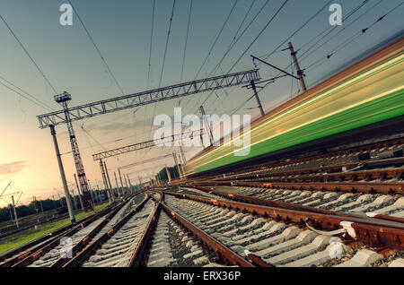 High-Speed-Personenzug auf Strecken mit Motion Blur-Effekt bei Sonnenuntergang. Bahnhof in der Ukraine Stockfoto