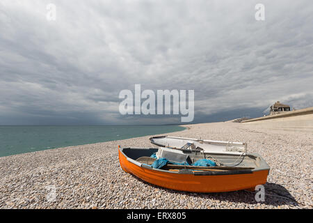 Zwei kleine Boote liegen am Kiesstrand bei strahlendem Sonnenschein mit drohenden Schlechtwetterfront Stockfoto