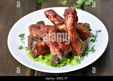 Geröstete Schweinerippchen auf weißen Teller über Holztisch Stockfoto