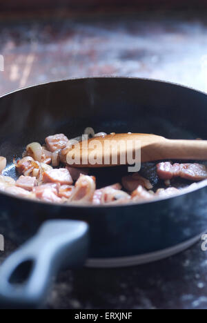 Still-Leben essen Bild der gewürfelten Speck und Schalotten in einer Pfanne braun / gebraten in Vorbereitung auf eine Brokkoli und Speck-Torte Stockfoto