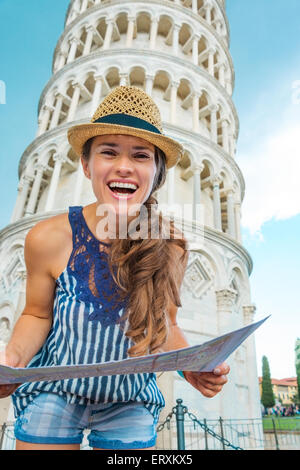 Eine glückliche Frau Tourist trägt einen Hut ist im Besitz einer Karte und lachen. Hinter ihr, der schiefe Turm von Pisa. Stockfoto