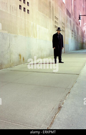 Ein Mann mit einem Fedora Hut stehen meist im Schatten. Stockfoto