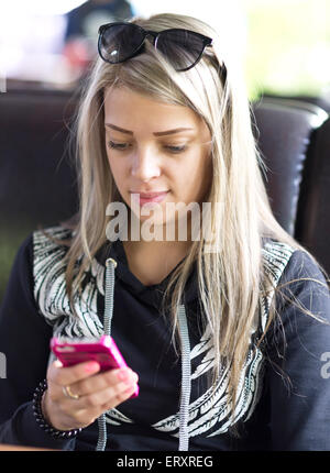 Mädchen sitzen im Café mit Handy Stockfoto