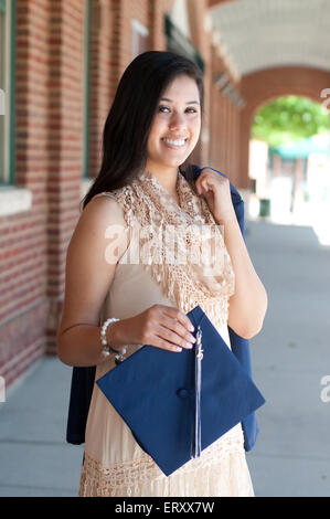 Im Freien Schuss von attraktiven High School Absolvent mit Graduierung Kleid. Stockfoto