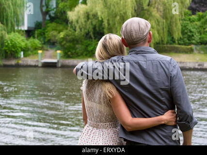 Rückseite eines Paares in einem Park steht am Wasser Stockfoto