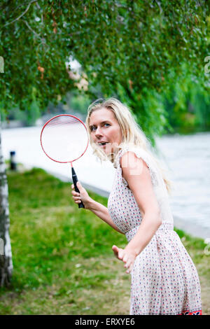 blonde Frau in einem Park Badminton spielen Stockfoto