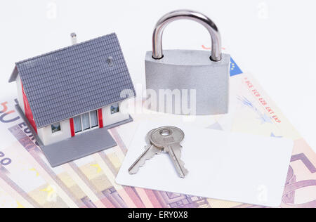 Bild zeigt ein Miniaturhaus ein geschlossenes Vorhängeschloss mit Plastikkarte auf rund Euro-Banknoten Stockfoto