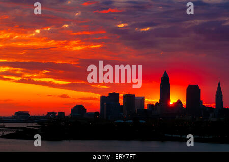 Die aufgehende Sonne späht heraus von hinten fast Silhouette Gebäude der Innenstadt von Cleveland Ohio Stockfoto