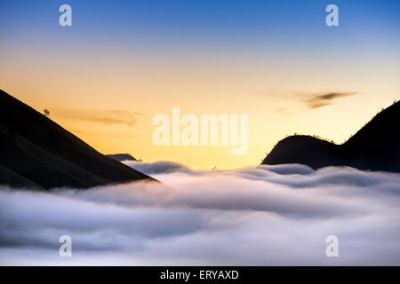 Berg-Silhouetten und Nebel im Tal auf den Sonnenaufgang im Bromo Tengger Semeru National Park in Java, Indonesien Stockfoto