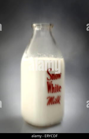 Milch in Glasflasche auf grauem Hintergrund Stockfoto