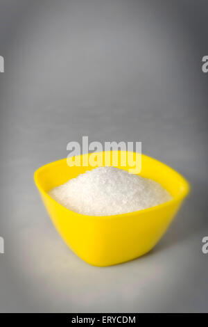 Zucker in gelbe Plastikbox auf grauem Hintergrund Stockfoto