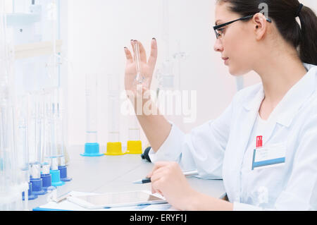 chemisches Laboratorium Szene: attraktive junge Studentin Wissenschaftler beobachten Flüssigkeit Maßnahmen, Medizin-Konzept Stockfoto