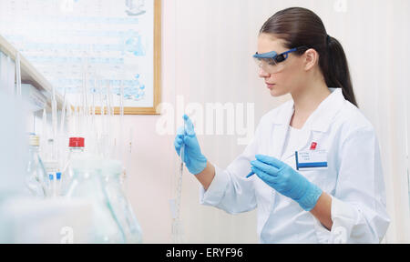 chemisches Laboratorium Szene: attraktive junge Studentin Wissenschaftler beobachten Flüssigkeit Maßnahmen, Medizin-Konzept Stockfoto