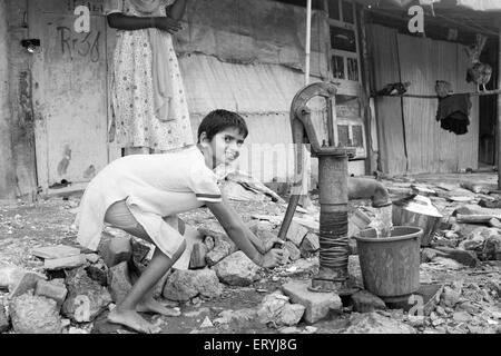 Mädchen, die Wasserpumpen aus Handpumpe; Malvani Slum; Malad; Bombay Mumbai; Maharashtra; Indien nicht Herr Stockfoto