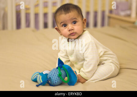 Sechs Monate altes Baby Mädchen auf dem Bett sitzend mit Kuscheltier, HERR#447G Stockfoto