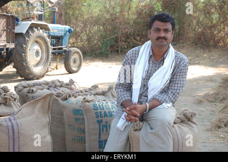 Indische Landwirt und Traktor, sitzt auf Jute Getreidesäcke, Singhpur, Bezirk Narsinghpur, Madhya Pradesh, Indien, Asien Stockfoto