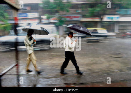 Pendler schützen sich mit ihren Regenschirmen, wie sie in heftige Regenfälle während der Monsunzeit in Bombay Fuß Stockfoto