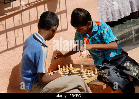 Schulkinder spielen Schach vor ihren Häusern in Bombay Mumbai Maharashtra indianerjungen, die Schach spielen Stockfoto