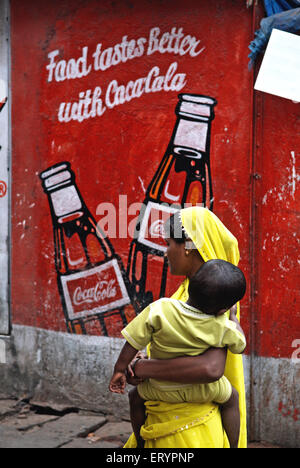 Coca Cola Werbung an der Wand gemalt , Frauen tragen Kind , Bombay , Mumbai ; Maharashtra ; Indien , Asien Stockfoto