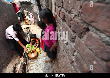 Wasserknappheit, Slum Menschen füllen Wasserkrug aus Rohr, Bombay, Mumbai; Maharashtra; Indien, Asien Stockfoto