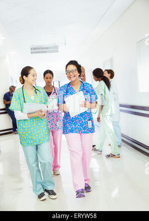 Lächelnde Krankenschwestern sprechen und Wandern im Krankenhausflur Stockfoto