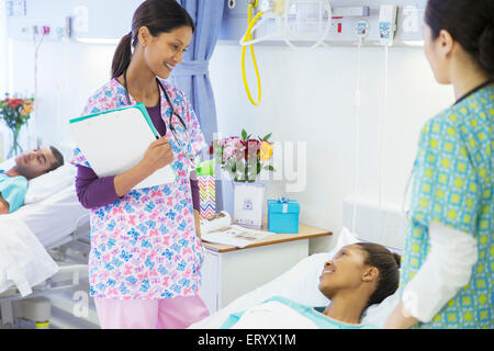 Lächelnde Krankenschwestern im Gespräch mit Patienten im Krankenzimmer Stockfoto