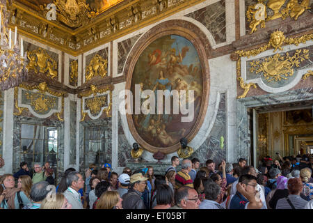 Touristen im Salon De La Paix du Château de Versailles mit dem 1729 ovale Gemälde von König Louis XV von François Lemoyne Stockfoto