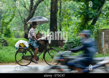 Lottery Ticketverkäufer Fahrrad mit Schirm im Regen; Kerala; Indien Stockfoto