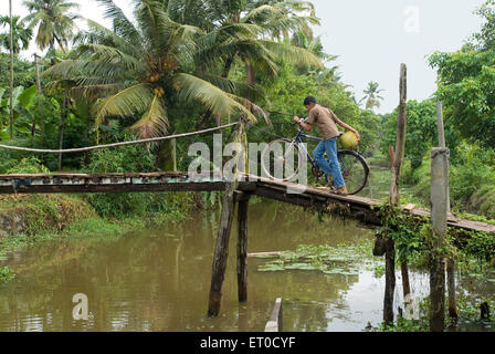 Junge mit Jackfrucht auf hölzerne Brücke in der Nähe von Alappuzha Alleppey-Zyklus; Backwaters von Kerala; Indien Stockfoto