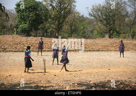 Schulmädchen spielen Cricket in Uniform auf trockenen Feldern in Jharkhand Indien indische Schulmädchen asiatisch spielen Cricket Stockfoto