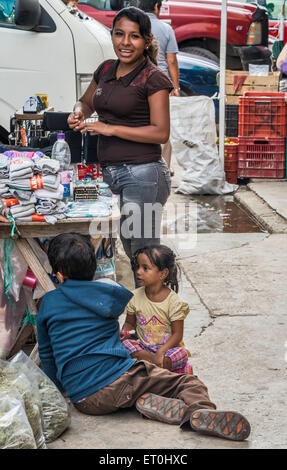 Junge Frau, die Kinder am Markt stall auf Calle 22, Straße in Ciudad del Carmen, Bundesstaat Campeche, Mexiko Stockfoto