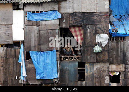 Ein Alter Mann sitzt an einer Tür Behrampada Slum in Bandra Bombay Mumbai Maharashtra Indien ersichtlich Stockfoto